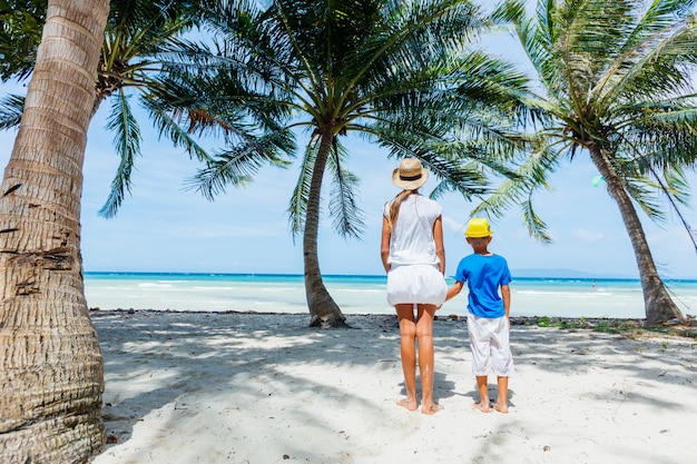 Śliczna siostra i brat bawią się na tropikalnej plaży z białym piaskiem z palmami