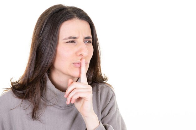 Śliczna tajemnicza kobieta pokazująca ciszę shh znak trzymający palec na ustach mający sekret na białym tle