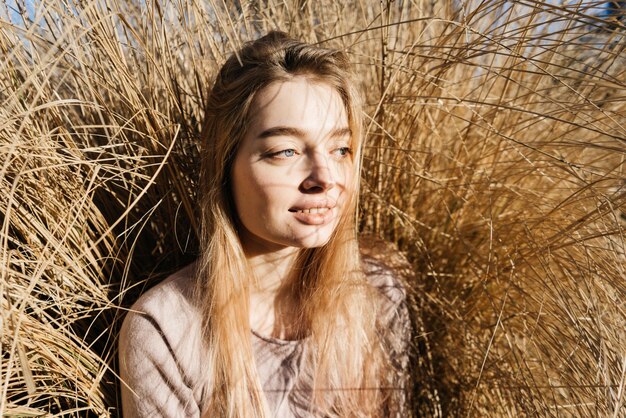 Śliczna uśmiechnięta dziewczyna blond modelka pozuje w słońcu na trawie