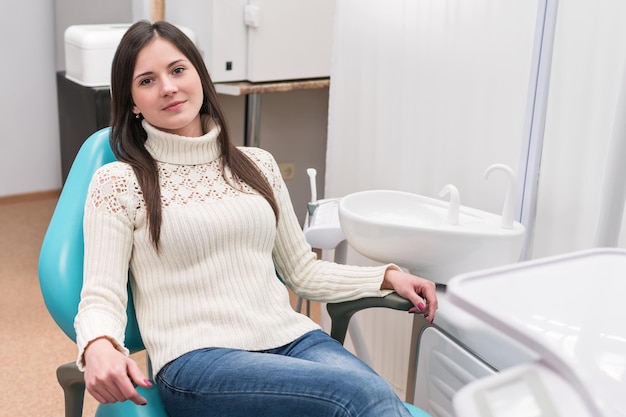 Śliczna uśmiechnięta dziewczyna siedzi na krześle u dentysty