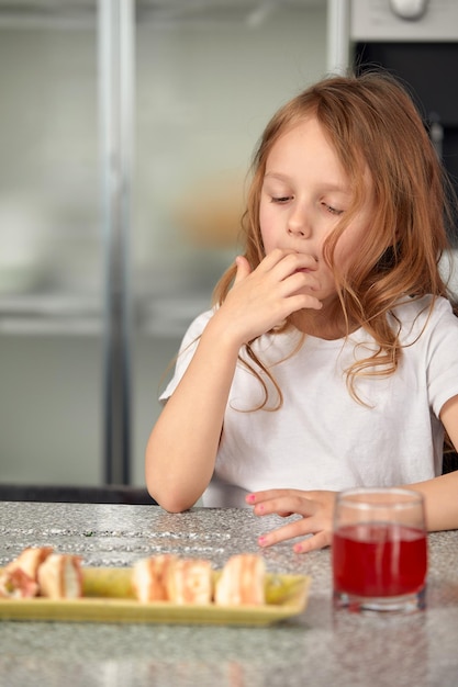 Śliczna uśmiechnięta dziewczynka z sushi na białym tle Dziewczynka jedząca sushi i bułki koncepcja komercyjna