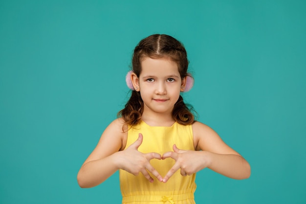 Śliczna uśmiechnięta mała dziewczynka robi heartshape gestowi