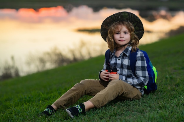 Śliczne blond dzieciak z lornetką na sobie kapelusz odkrywcy i plecak na charakter Dziecko odkrywca piesze wycieczki