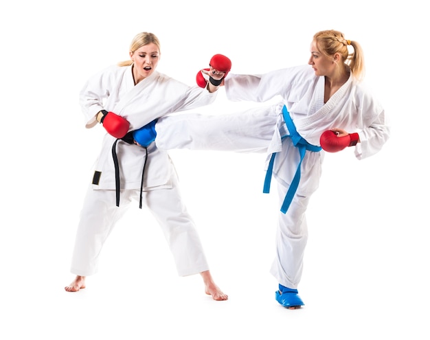 Śliczne blond dziewczyny karate są zaangażowane w trening w kimono na białym tle