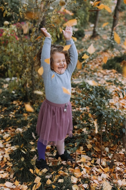 śliczne kręcone włosy mała dziewczynka rzuca liście w parku w czasie jesieni jesienny baner karta opieka zdrowotna