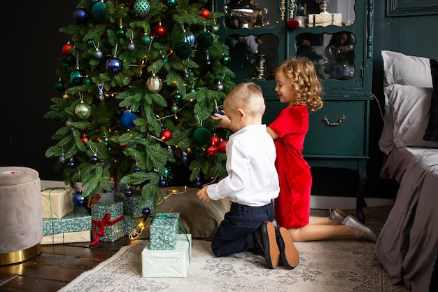 Zdjęcie Śliczne małe dzieci dekorujące choinkę wesołych świąt i wesołych świąt
