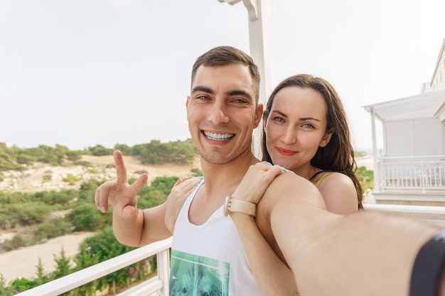 Śliczne selfie młodej pary, przytulanie i uśmiechając się do kamery, symbol pokoju