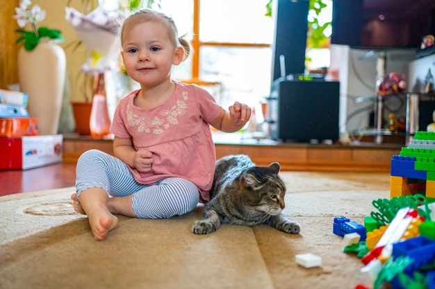 Śliczne urocze dziecko bawiące się pręgowanym nieszczęśliwym kotem w mieszkaniu z dziećmi dzieci i zwierzętami domowymi
