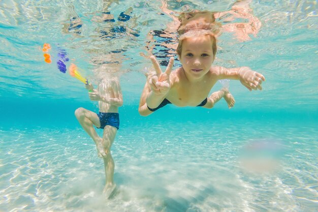 Śliczni chłopcy pływający pod wodą w płytkiej turkusowej wodzie na tropikalnej plaży