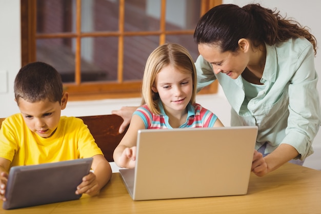 Śliczni ucznie w klasowym używa laptopie i pastylce z nauczycielem