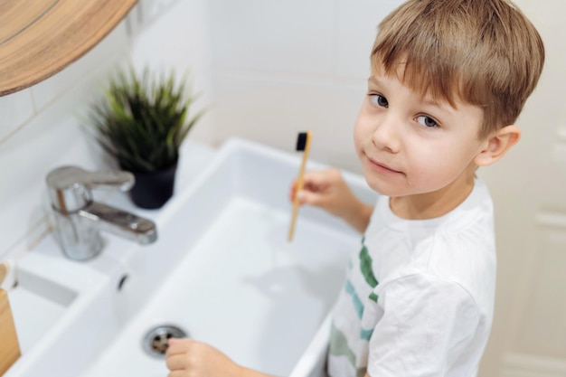 śliczny 6-letni chłopiec myjący twarz nad zlewem w łazience Obraz z selektywnym skupieniem