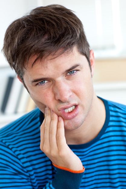 Śliczny caucasian mężczyzna ma toothache w pokoju