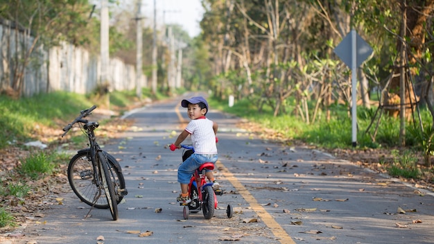 Śliczny Chłopiec Jedzie Bicykl Blisko Jego Ojca Dużego Roweru.