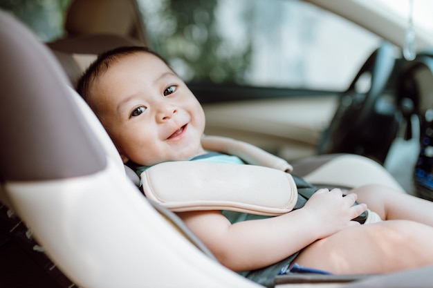 Śliczny chłopiec uśmiechający się w foteliku samochodowym Koncepcja bezpieczeństwa transportu dziecka