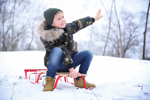 Śliczny Chłopiec Z Saniami W Snowy Parku Na Ferie Zimowe