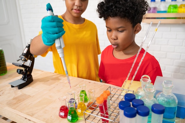 Śliczny chłopiec z włosami afro i siostra studiują naukę z testową substancją chemiczną w szklanych naczyniach