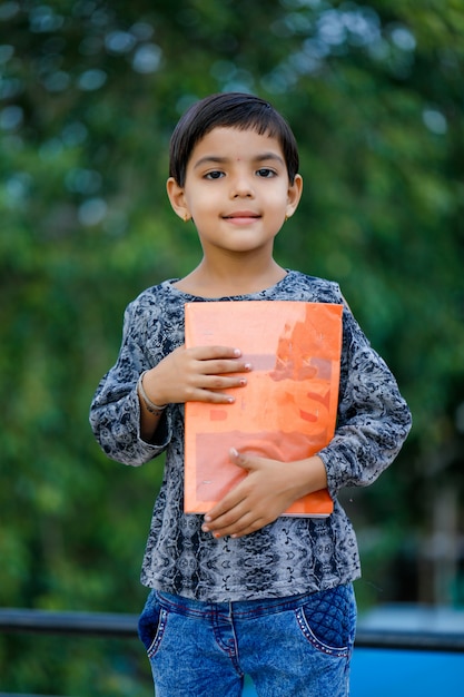 Śliczny indyjski dziecko trzyma szkolną książkę