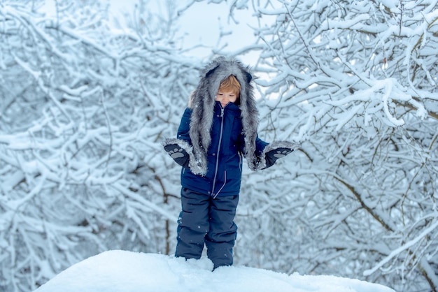 Śliczny maluch chłopiec bawi się w winter park w śniegu na zewnątrz dzieci w zimowych ubraniach wspomnienia z dzieciństwa ...