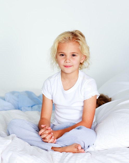 Śliczny mały blond dziewczyny obsiadanie na jej łóżku