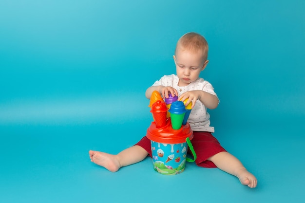 Śliczny mały chłopiec bawi się plastikowymi zabawkami siedząc na podłodze Wczesna nauka Rozwijanie zabawek