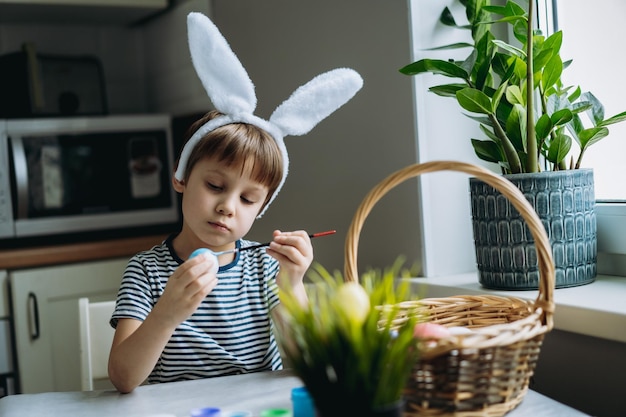 Śliczny mały chłopiec koloruje jajka na Wielkanoc