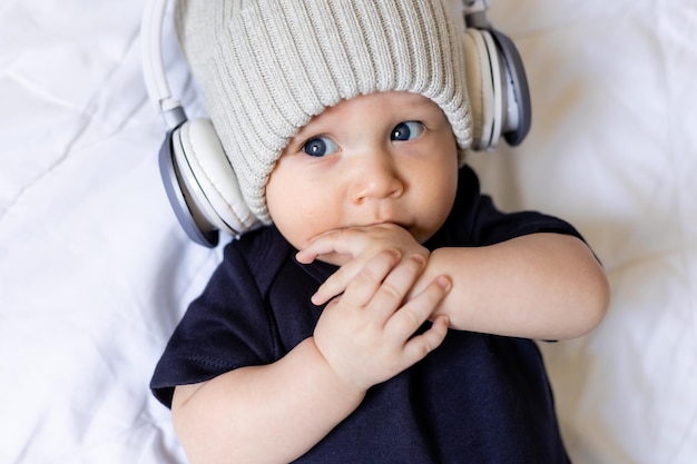 Śliczny mały chłopiec w kapeluszu ze słuchawkami leżącymi na kocu, karcie, miejscu na tekst, banerze
