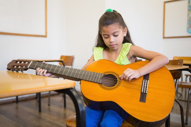 Śliczny Uczeń Bawić Się Gitarę W Sala Lekcyjnej