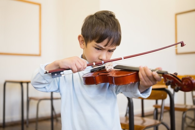 Śliczny uczeń bawić się skrzypce w sala lekcyjnej