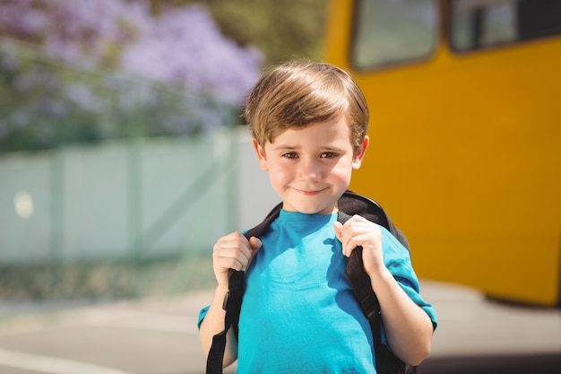Śliczny uczeń ono uśmiecha się przy kamerą autobusem szkolnym