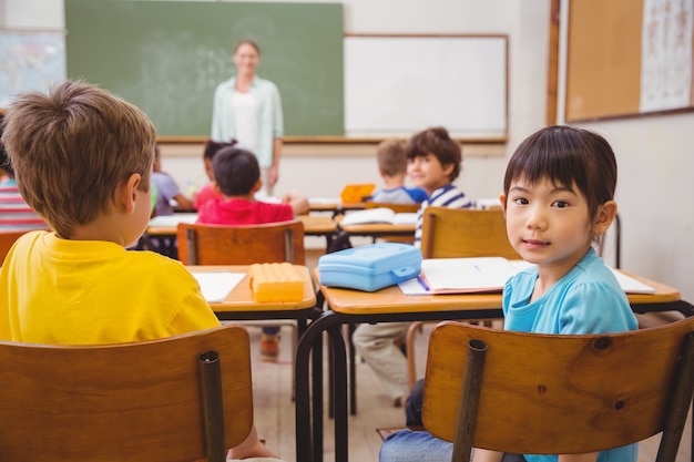 Śliczny uczeń ono uśmiecha się przy kamerą w sala lekcyjnej