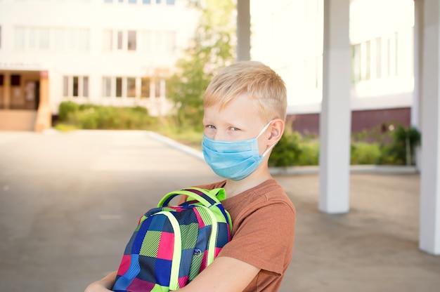 Śliczny uczeń z maską ochronną i plecakiem