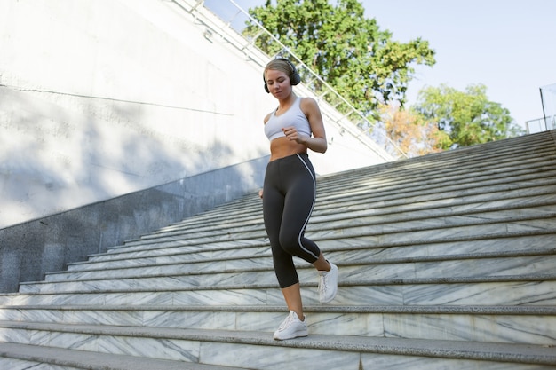 Slim fit kobieta w odzieży sportowej biegnie po schodach na zewnątrz. Koncepcja zdrowego stylu życia