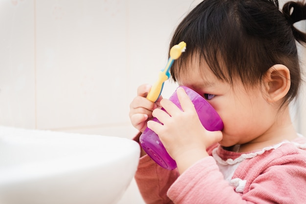 Słodka Azjatycka dziecko mała dziewczynka szczotkuje jej zęby w łazience