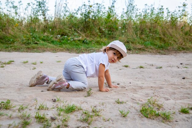 Zdjęcie słodka dziewczyna czołgająca się po piasku na plaży