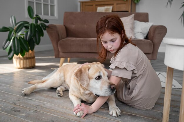 Słodka dziewczyna i labrador retriever w domu.