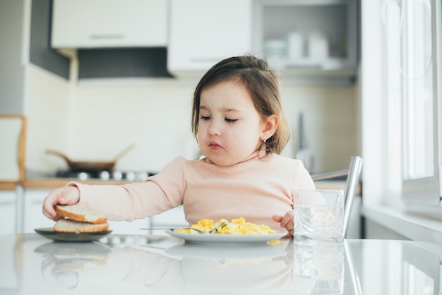 Słodka dziewczyna w kuchni je chleb i omlet