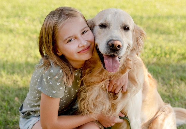 Słodka dziewczynka w wieku preteen przytulająca psa golden retriever w naturze Ładny dzieciak z rasowym pieskiem