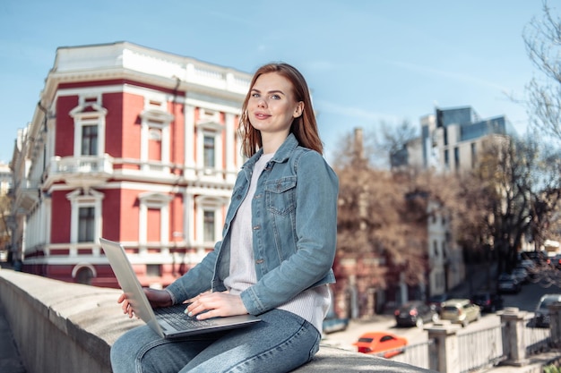 Słodka kaukaska długowłosa kobieta używająca laptopa w mieście