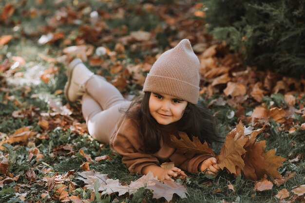 Słodka mała brunetka leżąca na trawie jesienią