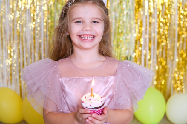 Zdjęcie słodka mała dziewczynka dmucha świecą na ciasteczku urodzinowym i świętuje urodziny