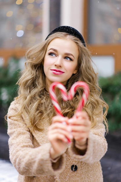 Słodka, marząca dziewczyna, młoda kobieta trzymająca lizak w kształcie serca w zimowy dzień.