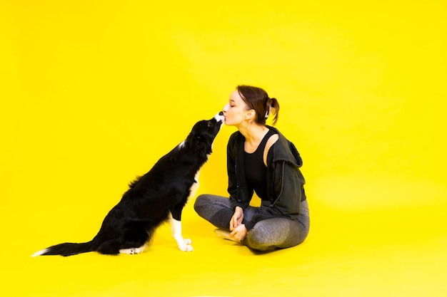 Słodka młoda kobieta całuje i przytula swojego szczeniaka border collie. Miłość między właścicielem a psem.