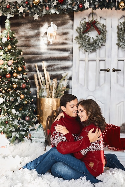 Słodka para kochanków w świątecznych ubraniach pozuje w świątecznym wnętrzu