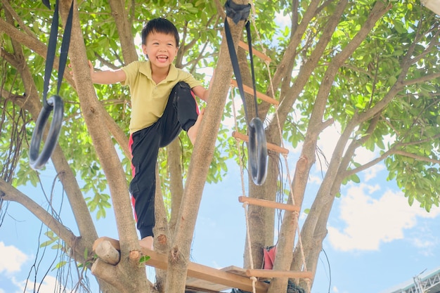 Słodki azjatycki chłopiec w wieku przedszkolnym dziecko bawiące się w obliczu wyzwania próbującego wspiąć się na drzewo w domu na podwórku na przyrodzie Gra bezpłatna Praktyka wczesnego dzieciństwa Zabawa na świeżym powietrzu dla zdrowych małych dzieci
