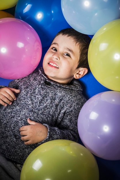 Słodki chłopiec bawi się balonami w wielu kolorach