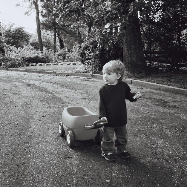 Zdjęcie słodki chłopiec ciągnie go-kart na drodze