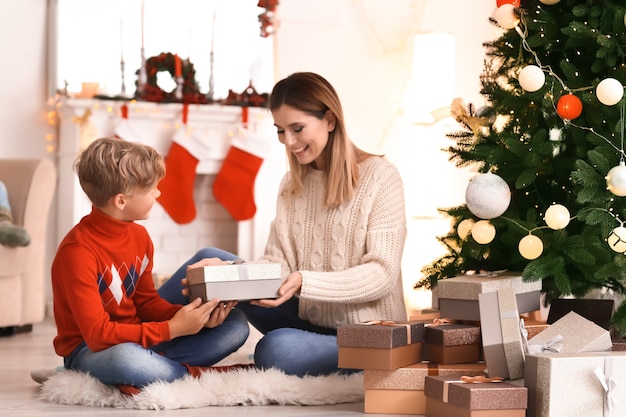 Słodki chłopiec i jego mama z prezentami świątecznymi w domu