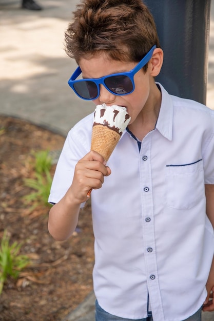 Słodki chłopiec z brudną twarzą je lody, a dziecko lubi deser.