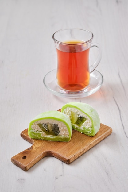 Słodki deser mochi z kiwi pokrojonym na pół z owocową herbatą