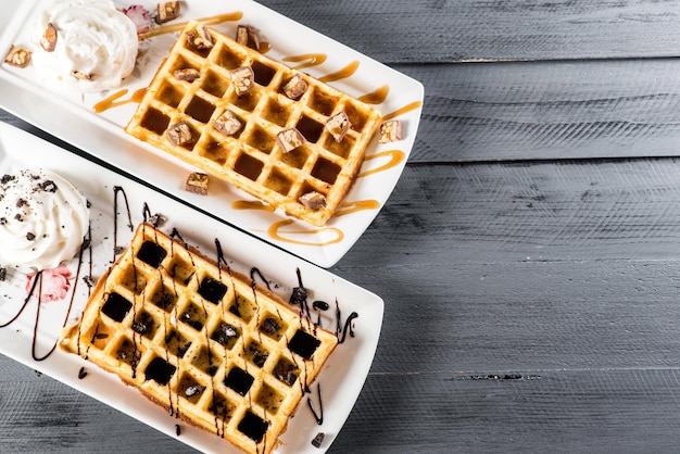 Słodki deser waflowy z czekoladą i lodami na drewnianym tle